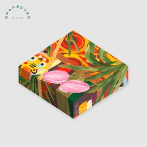 May include: A colorful, abstract art box with a tiger face design on one side. The box features pink shapes, green leaves, and a vibrant mix of red, yellow, and orange patterns. The text "BEAUBOURG ART EDITIONS" is visible.