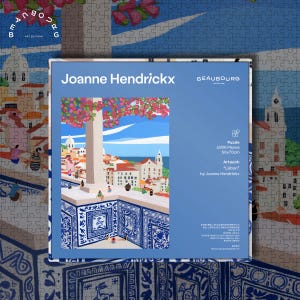 May include: A 1000-piece jigsaw puzzle featuring the artwork "Lisbon" by Joanne Hendrickx. The puzzle image depicts a scenic view of a city with red-roofed buildings, blue accents, and the text "Joanne Hendrickx" and "BEAUBOURG". The puzzle measures 50x70cm.