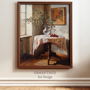 Puede incluir: Pintura enmarcada de un bodegón. Una mesa redonda con un mantel floral sostiene un jarrón de cristal con ramas de acebo y bayas rojas. Una pintura enmarcada más pequeña cuelga de la pared. El texto "OSMANTHUS Art Design" está en la parte inferior.