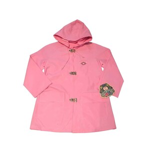 Peut inclure: Un imperméable rose à capuche avec une fermeture à bascule et deux poches avant. Le manteau a un petit emblème sur la poitrine et une étiquette sur la manche. L'imperméable est en matière imperméable.
