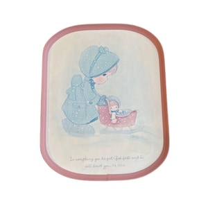 May include: A decorative tray with a pink border features a pastel illustration of a child pushing a baby in a sleigh. The child wears a blue coat and hat with white polka dots. The tray has text that reads, "In everything you do put God first; and he will direct you. Ph 3:6".