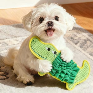 May include: A small, white dog with a happy expression holds a green and yellow alligator-shaped dog toy. The toy has a textured body and a ruffled tail. The dog is sitting on a gray rug.