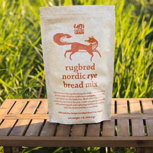 Puede incluir: Una bolsa de papel color canela de mezcla para pan de centeno nórdico rugbrød 40 Century Grain con una ilustración de un zorro naranja. El texto dice: rugbrød nordic rye bread mix, net weight 454.4 g, y detalles sobre la harina.