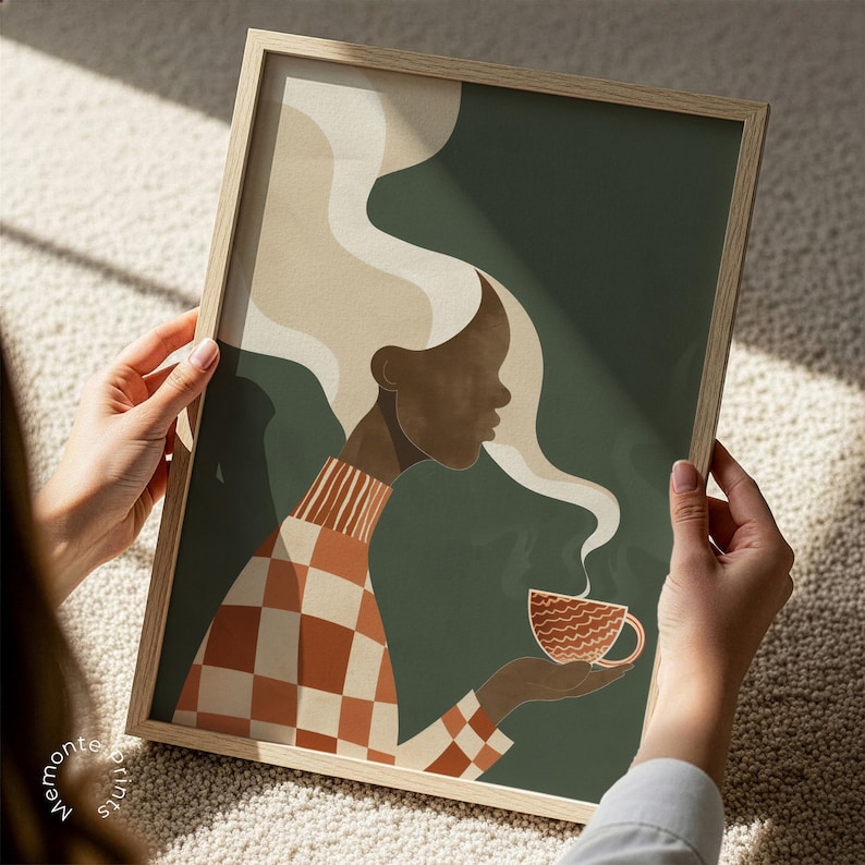 May include: A framed art print featuring a stylized illustration of a person with dark skin and long, flowing hair. The person is wearing a checkered orange and white sweater and holding a steaming cup of coffee. The background is a dark green.