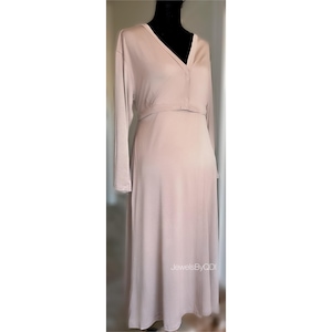 May include: A long, pale pink dress with long sleeves and a V-neck. The dress has a fitted bodice and a flowing skirt. The text "JewelsByQDI" is visible on the lower right side of the dress.