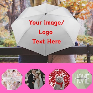 Puede incluir: Un paraguas plegable blanco con el texto rojo Your Image/ Logo Text Here impreso en la cubierta. Debajo, cuatro ejemplos muestran diseños personalizados que incluyen un collage de fotos, un retrato de boda, un gato y la palabra HOME.