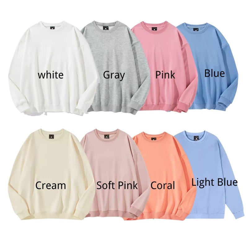 May include: A collection of eight crewneck sweatshirts in various colors: white, gray, pink, blue, cream, soft pink, coral, and light blue. Each sweatshirt has the color name printed on it.