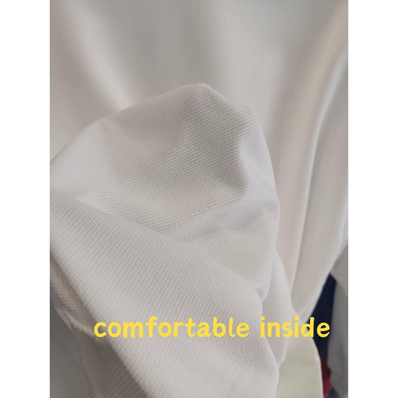 May include: Close-up of white fabric with a textured, waffle-like weave. The words "comfortable inside" are printed in yellow. The fabric appears soft and lightweight, suggesting a garment.