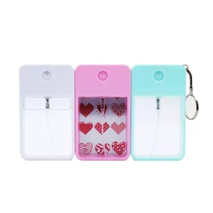 Könnte beinhalten: Drei rechteckige, nachfüllbare Sprühflaschen in Weiß, Rosa und Türkis. Die rosa Flasche hat ein Herzdesign. Jede Flasche hat einen transparenten Abschnitt für die Flüssigkeit und eine silberne Sprühdüse. Die türkisfarbene Flasche hat einen kleinen silbernen Schlüsselanhänger.