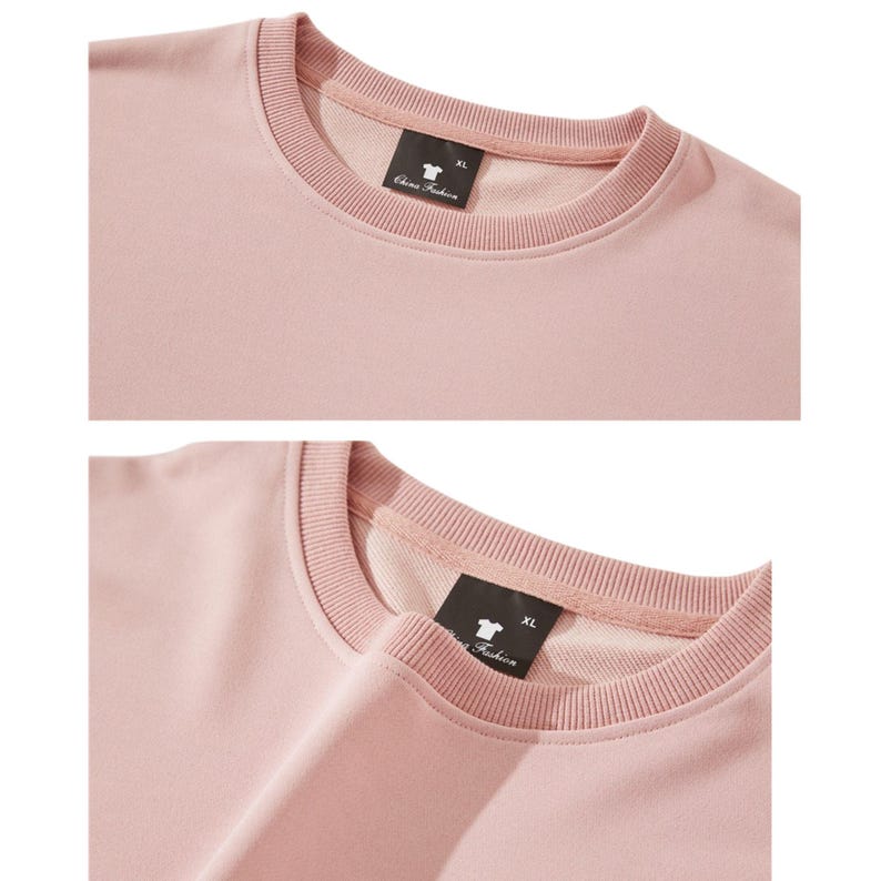 May include: A close-up of a light pink crew neck sweatshirt. The sweatshirt has a ribbed neckline and cuffs. A black tag with white text and a logo is visible on the inside of the neckline. The tag reads "China Fashion" and "XL".