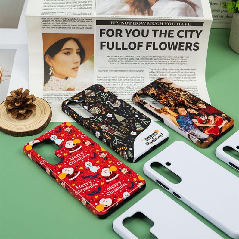 May include: A collection of phone cases with various designs, including a red case with Santa Claus and the text "Merry Christmas". Other cases feature patterns and a photo. The cases are displayed on a green surface.