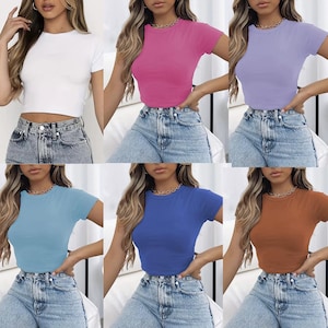 Puede incluir: Colección de seis tops cortos de manga corta en varios colores: blanco, rosa, lavanda, azul claro, azul real y marrón. Cada top tiene cuello redondo y se combina con vaqueros de mezclilla de lavado claro.