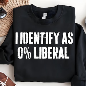 May include: Black sweatshirt with the white text "I IDENTIFY AS 0% LIBERAL". The sweatshirt is a crew neck style. The text is in a bold, distressed font.