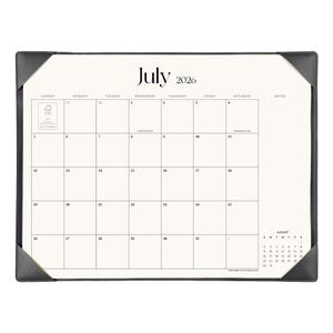 May include: A desk calendar for July 2026 featuring a white grid layout with black text, including a notes section and a small August 2026 calendar preview. The calendar is held in place by dark gray corner protectors on a rectangular frame.