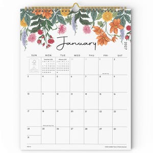 May include: A 2027 wall calendar for the month of January featuring a floral illustration at the top with orange, pink, and yellow flowers and green leaves. The grid displays days of the week, dates, and small reference calendars for December 2026 and February 2027.