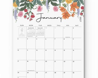 Könnte beinhalten: Ein Wandkalender für Januar 2027 mit einer floralen Illustration am oberen Rand, bestehend aus orangefarbenen, rosafarbenen und gelben Blumen sowie grünen Blättern. Das Raster zeigt Wochentage, Daten und kleine Referenzkalender für Dezember 2026 und Februar 2027.