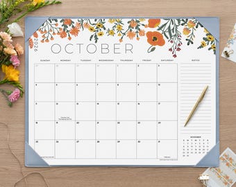 May include: A 2026 desk calendar for the month of October featuring a floral border with orange and yellow flowers. The calendar has a grid layout with a notes section on the right side and a small November calendar at the bottom right corner.