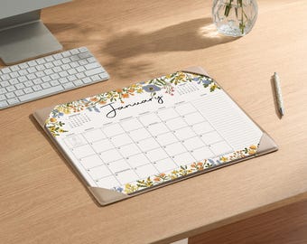 May include: A rectangular desk calendar pad for the month of January, featuring a white background with a colorful floral border of yellow, orange, and blue flowers. The grid layout includes days of the week, a notes section, and a small calendar.