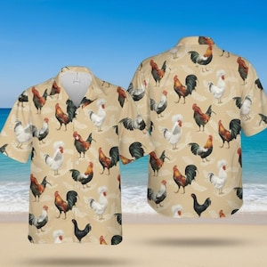 Puede incluir: Dos camisas de manga corta con botones con un estampado de gallo. Las camisas son de color beige con un patrón repetido de gallos coloridos. El fondo muestra una playa y el océano.