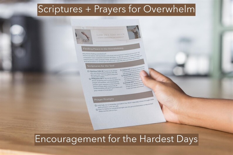May include: A printed page titled "Scriptures + Prayers for Overwhelm" and "Encouragement for the Hardest Days" is held by a hand. The page contains text about finding peace and scriptures for the soul. The background is a blurred interior.