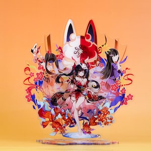May include: A colorful acrylic stand featuring a detailed anime-style illustration of a female character in a red and black outfit, surrounded by floral and decorative elements. The stand has a clear base and a vibrant orange background.