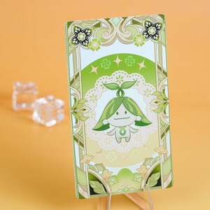Puede incluir: Una tarjeta rectangular con un personaje de dibujos animados con pelo verde y cuerpo blanco, sobre un fondo blanco y verde. La tarjeta tiene un borde decorativo con motivos florales y de hojas. La combinaci&oacute;n de colores general es verde y blanco.