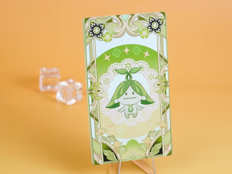 Puede incluir: Una tarjeta rectangular con un personaje de dibujos animados con pelo verde y cuerpo blanco, sobre un fondo blanco y verde. La tarjeta tiene un borde decorativo con motivos florales y de hojas. La combinaci&oacute;n de colores general es verde y blanco.