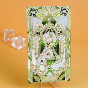 Puede incluir: Una tarjeta rectangular con un personaje de estilo anime con cabello blanco y ropa verde. La tarjeta tiene un borde decorativo verde y beige con patrones florales y geom&eacute;tricos. El fondo es de color naranja s&oacute;lido.