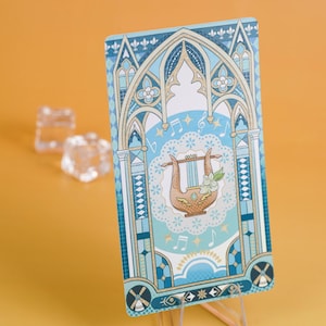 Puede incluir: Una tarjeta decorativa con una ilustraci&oacute;n de lira dentro de un dise&ntilde;o de arco g&oacute;tico azul y blanco. La tarjeta tiene notas musicales y detalles florales. El fondo es de color azul claro y la tarjeta se muestra sobre un soporte transparente.