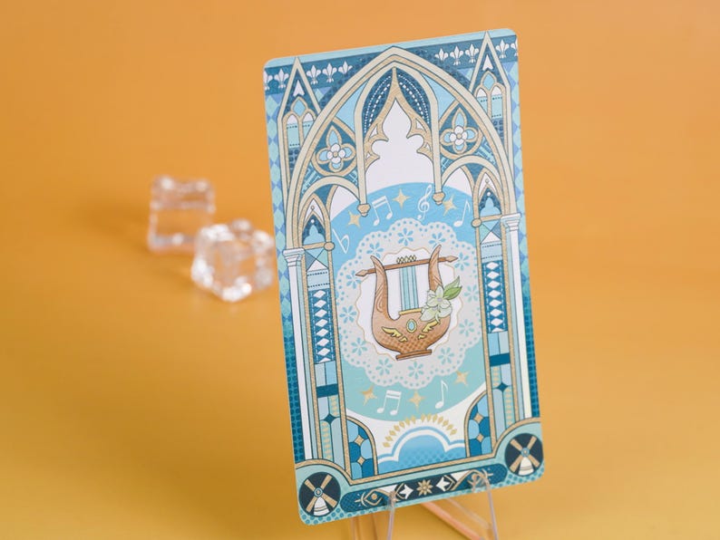 Puede incluir: Una tarjeta decorativa con una ilustraci&oacute;n de lira dentro de un dise&ntilde;o de arco g&oacute;tico azul y blanco. La tarjeta tiene notas musicales y detalles florales. El fondo es de color azul claro y la tarjeta se muestra sobre un soporte transparente.