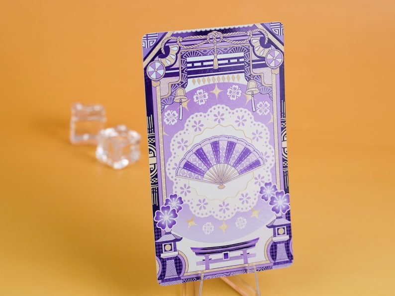 Puede incluir: Una tarjeta rectangular con un dise&ntilde;o de inspiraci&oacute;n japonesa en tonos morados y blancos. La tarjeta presenta un abanico, flores de cerezo y elementos arquitect&oacute;nicos. El fondo es de color naranja liso.