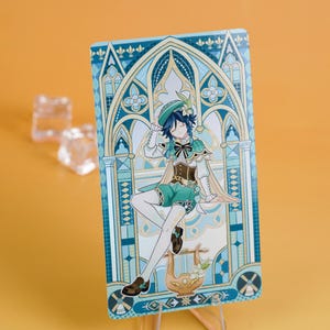 Puede incluir: Una tarjeta rectangular con una ilustraci&oacute;n de personaje. El personaje viste un atuendo verde y blanco, sentado frente a un arco decorativo. La tarjeta tiene una combinaci&oacute;n de colores azul y dorado, con una lira en la parte inferior. La tarjeta est&aacute; apoyada.