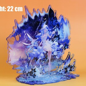 Op de afbeelding: Decoratieve acryl figuur met een hemels ontwerp, met een vrouwelijk figuur, vlinders en bloemmotieven. De figuur is blauw en wit, met een hoogte van 22 cm.