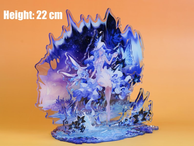 Op de afbeelding: Decoratieve acryl figuur met een hemels ontwerp, met een vrouwelijk figuur, vlinders en bloemmotieven. De figuur is blauw en wit, met een hoogte van 22 cm.