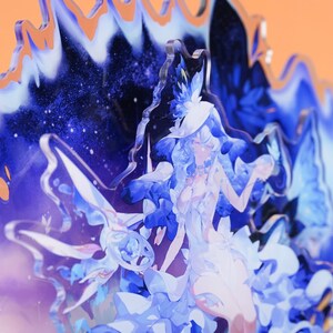 Op de afbeelding: Een gelaagd acryl kunstwerk met een hemels ontwerp met een vrouw in een witte jurk en hoed. Het kunstwerk is overwegend blauw en wit, met een sterrenachtergrond en een golvende, getextureerde rand.