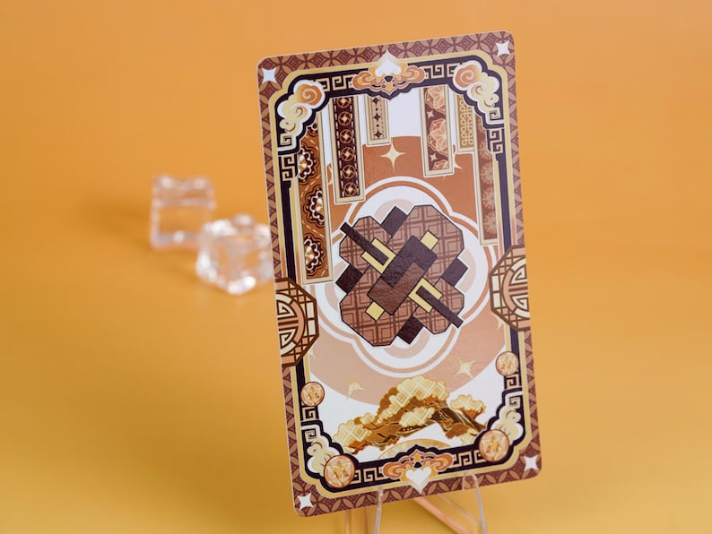 Puede incluir: Una tarjeta decorativa con un dise&ntilde;o marr&oacute;n y beige, con patrones geom&eacute;tricos y motivos de nubes. La tarjeta tiene forma rectangular y se muestra sobre un soporte transparente sobre un fondo naranja.