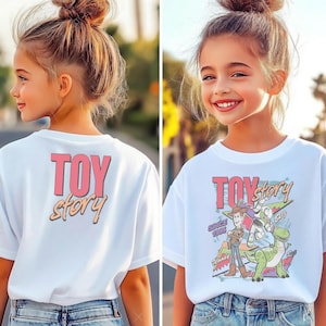May include: White t-shirt featuring the text "TOY STORY" in pink and orange. The front of the shirt has a graphic of characters from the movie, including Woody, Buzz Lightyear, and Rex. The shirt is worn by a young person.