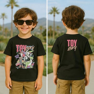 May include: Black t-shirt featuring a colorful graphic of Toy Story characters, including Woody and Buzz Lightyear, with the text "TOY STORY" and "SINCE 1995". The back of the shirt displays the text "TOY story" in pink and white.