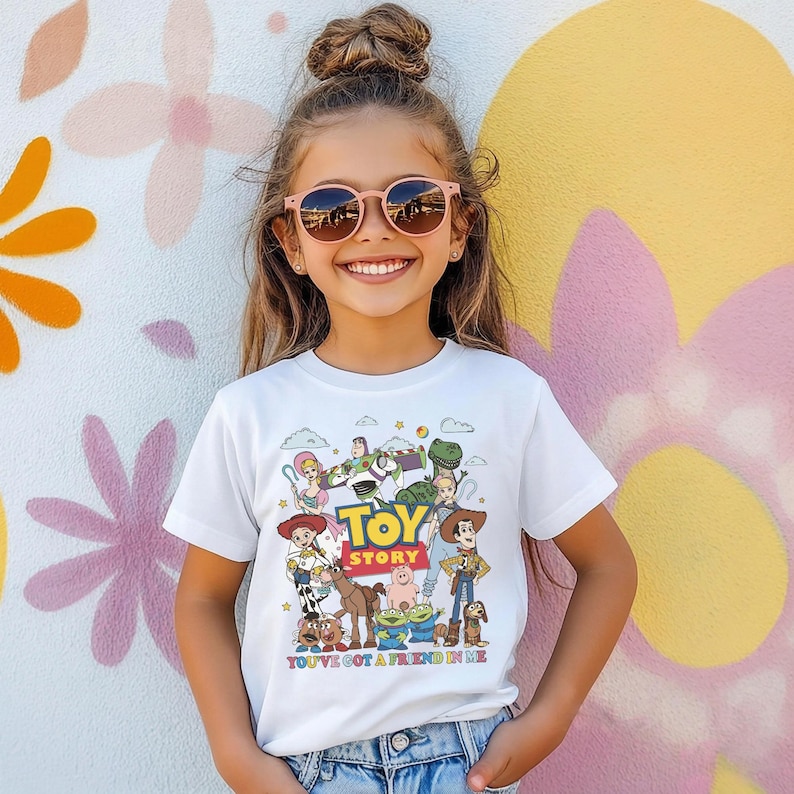 Op de afbeelding: Wit T-shirt met een kleurrijke afbeelding van personages uit de animatiefilm "Toy Story". Het ontwerp bevat de filmtitel en de zin "You've Got a Friend in Me".