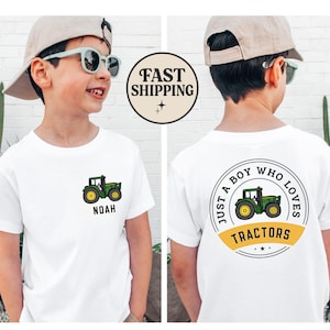 May include: White t-shirt with a green and yellow tractor graphic. The front of the shirt has the name "Noah" below the tractor. The back of the shirt says "Just a boy who loves tractors" in a circular design.