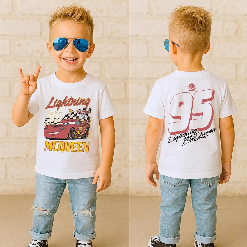 May include: A white t-shirt featuring Lightning McQueen from the Cars movie. The front of the shirt displays McQueen with the text "Lightning McQueen". The back of the shirt shows the number "95" and the text "Lightning McQueen". The child is wearing blue jeans.