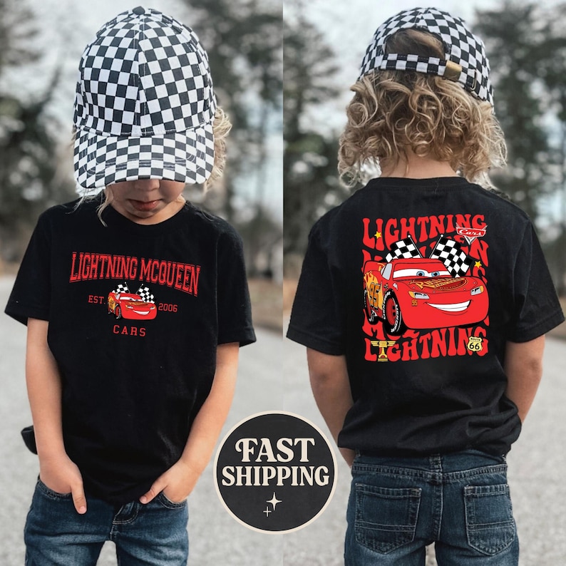 Puede incluir: Camiseta negra con Lightning McQueen de la pel&iacute;cula Cars. El frente muestra "Lightning McQueen" y "Cars". La parte trasera muestra a McQueen con banderas a cuadros y el texto "Lightning". El ni&ntilde;o lleva una gorra a cuadros en blanco y negro.