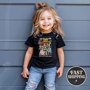 Puede incluir: Una camiseta negra con un gr&aacute;fico colorido de personajes de la pel&iacute;cula animada "Toy Story". La camiseta tiene el texto "TOY STORY" y "YOU'VE GOT A FRIEND IN ME". El ni&ntilde;o lleva vaqueros azules.