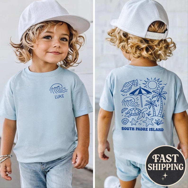 Op de afbeelding: Lichtblauw T-shirt met een golfpatroon en de naam "LUKE" op de voorkant. De achterkant toont een blauwe illustratie van een strandsc&egrave;ne met een schildpad, palmbomen en de tekst "SOUTH PADRE ISLAND".