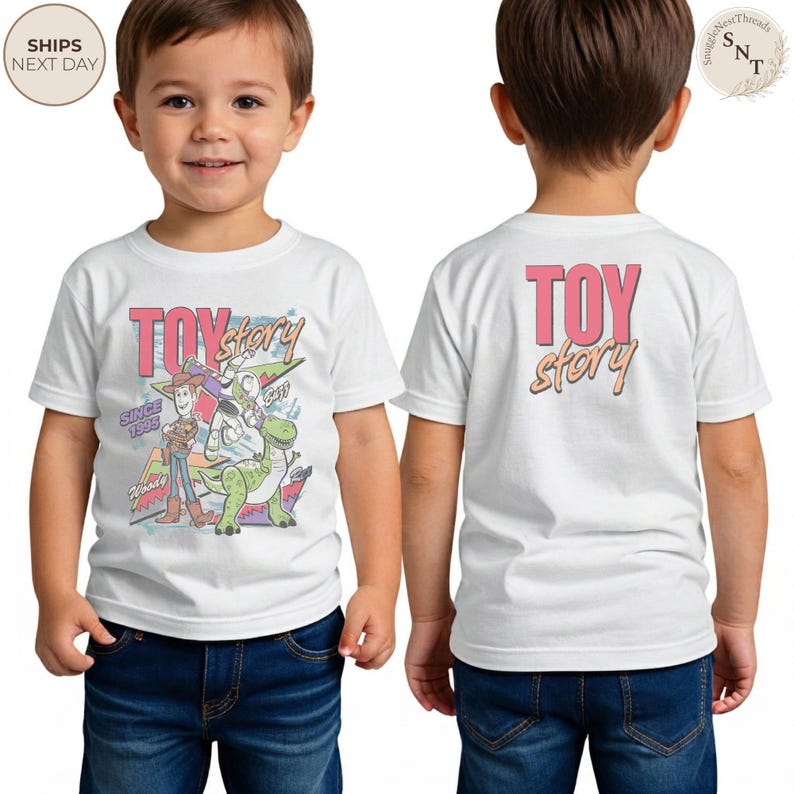 May include: White t-shirt featuring the words "TOY STORY" in pink and orange, with a graphic of Woody, Buzz Lightyear, and Rex. The front of the shirt has the text "SINCE 1995". The back of the shirt has the words "TOY STORY".