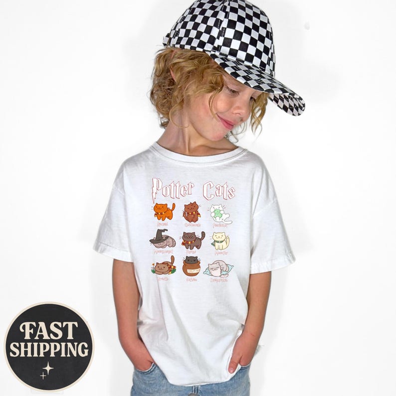 May include: A white t-shirt featuring the text "Potter Cats" above a grid of cartoon cat illustrations. The cats are in various colors and poses. The person is wearing a black and white checkered baseball cap.