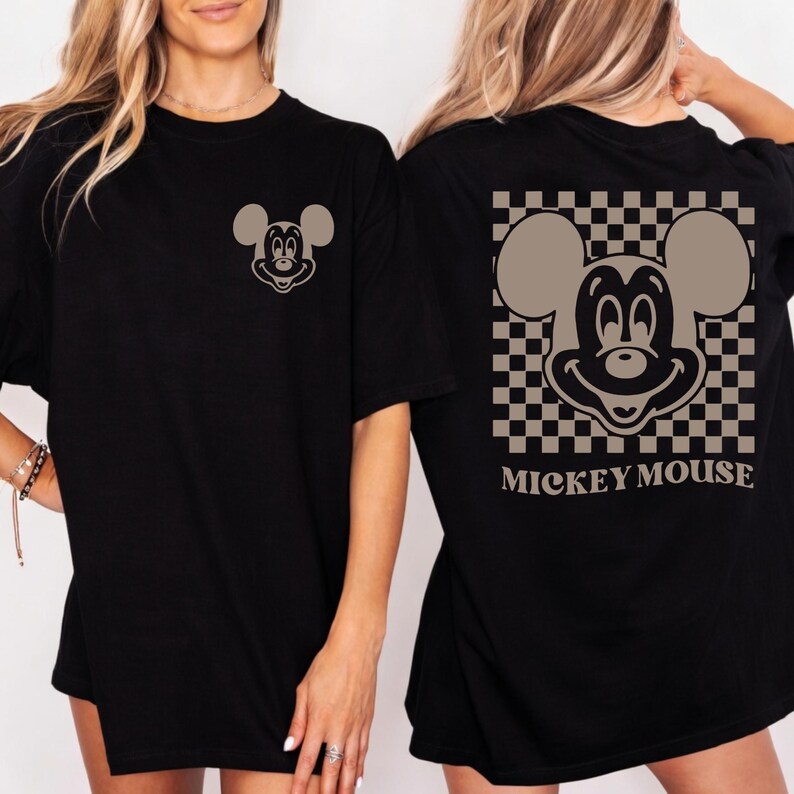 May include: Black t-shirt featuring a Mickey Mouse graphic. The front of the shirt has a small Mickey Mouse design, while the back showcases a larger Mickey Mouse image within a checkered pattern, with the words "Mickey Mouse" below.