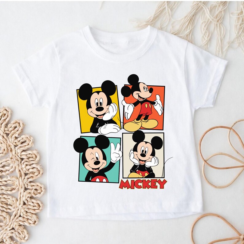 May include: White t-shirt with a colourful graphic of Mickey Mouse in four different poses. Each pose is set within a square of yellow, orange, teal, and beige. The word "MICKEY" is printed in red below the images.