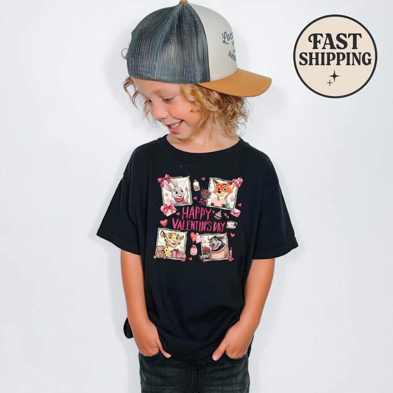May include: A black t-shirt featuring a colorful graphic with the text "Happy Valentine's Day." The graphic includes cartoon animals in frames with hearts and gifts. The child is wearing a trucker hat.