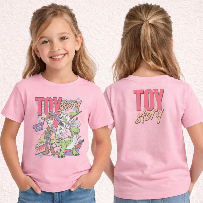 May include: Pink short-sleeved t-shirt featuring the words "Toy Story" in pink and yellow, with cartoon characters Woody, Buzz Lightyear, and Rex. The shirt also has the text "Since 1995". The back of the shirt has the words "Toy Story".